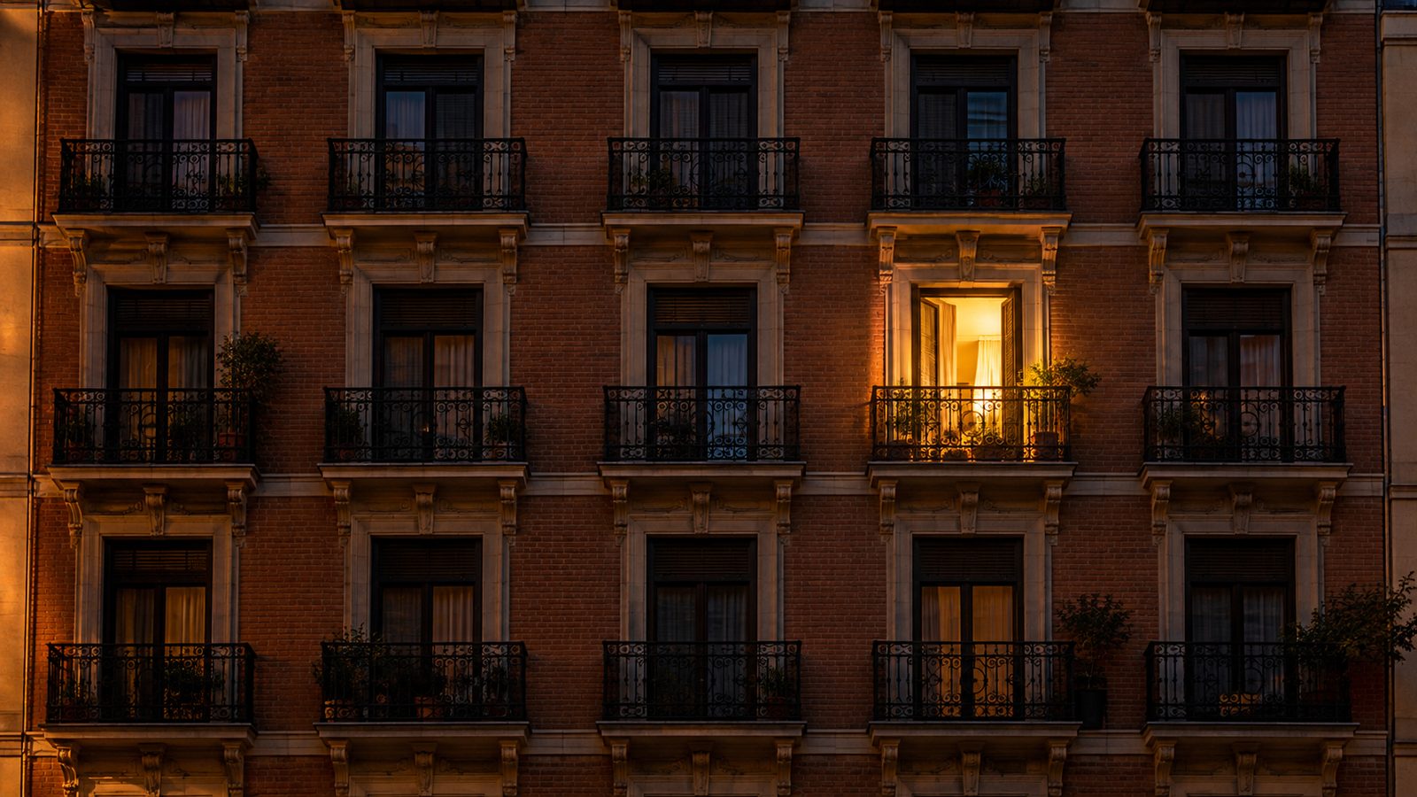 Fachada de una finca de Madrid con balcones iguales y una sola ventana iluminada